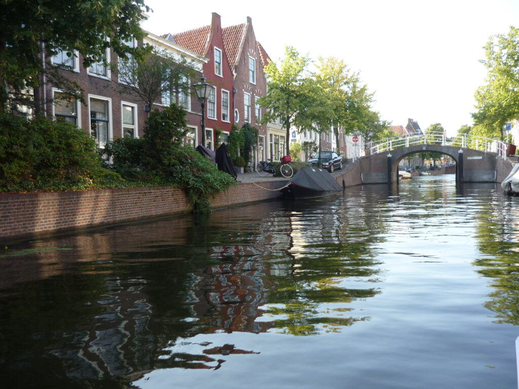 Canal with houses on one side and bridge coming up in Leiden, The Netherlands