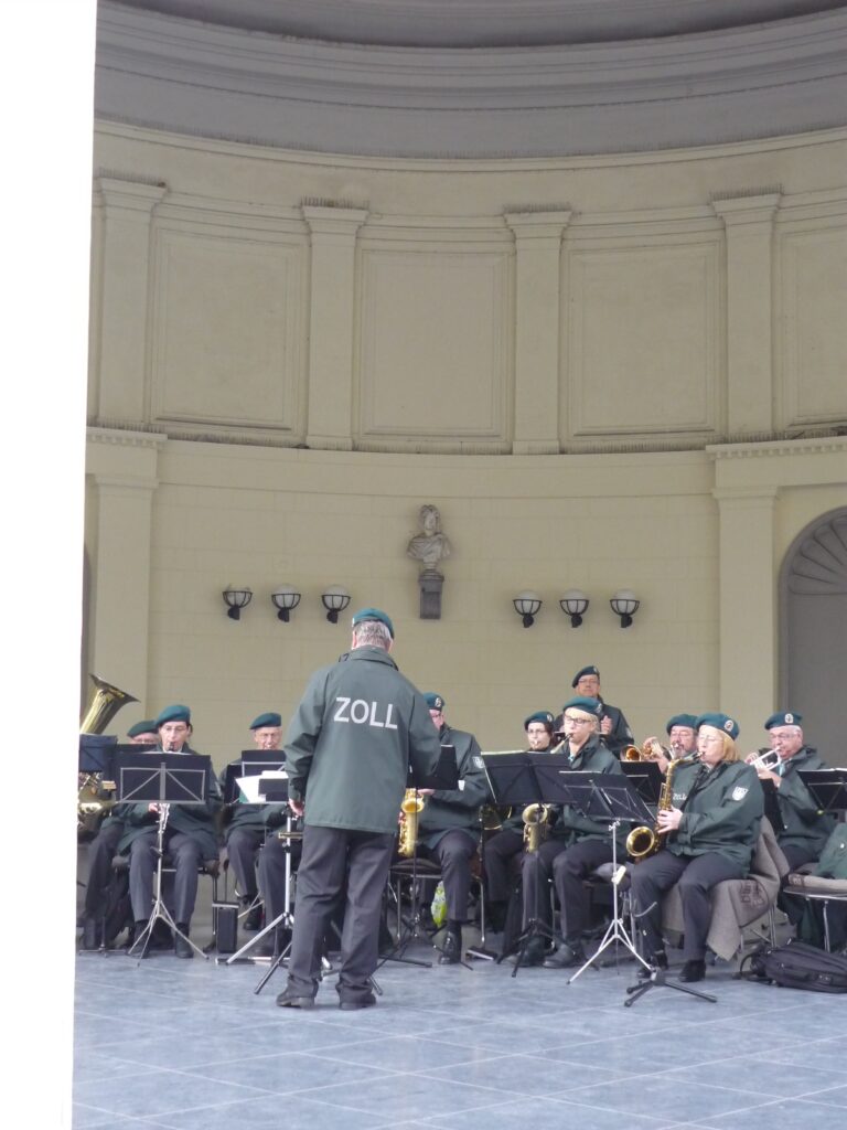 Band playing in a cupola. Conductor wears a jacket that says "ZOLL" which means Customs.