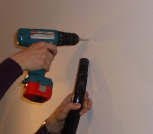 Drilling a hole in the wall with an electric drill.