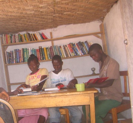 young people reading at a table with bookcase