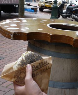 poppy seed bagel next to bagel shaped table with bite out of it