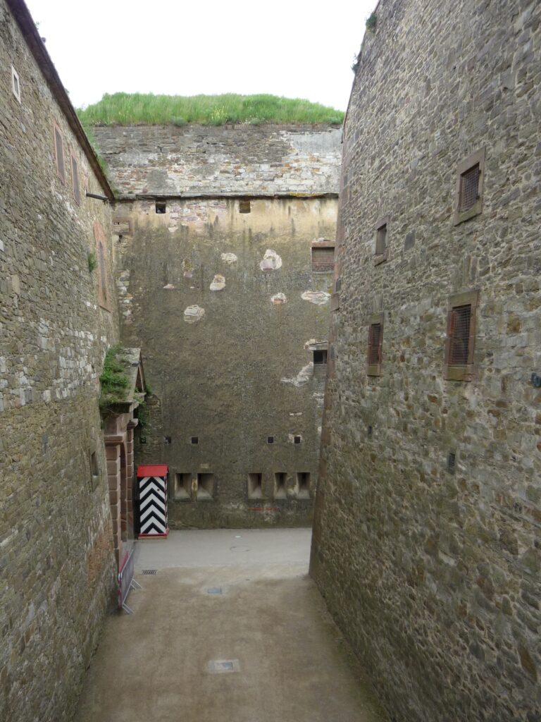 Passageway that turns right into a passage you can't yet see. Towering interior walls of a fortress in Koblenz block your view in all directions..