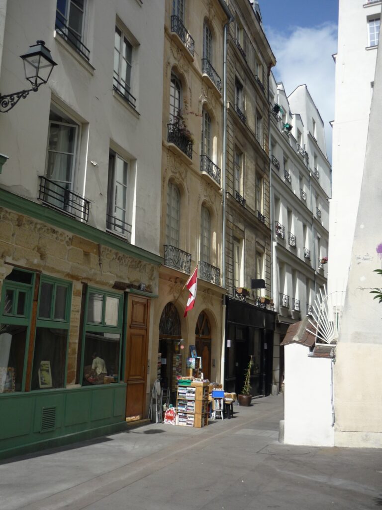 Bookstore with Canadian flag and used books stacked outside on the pavement.