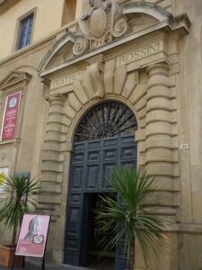 Front door of Rossini Theater with palm tree and poster for Rossini Opera Festival