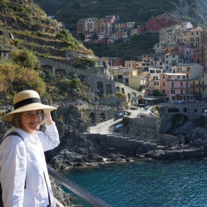 Laurel Decher in foreground with colorful houses of Vernazza, Italy and blue Riviera behind