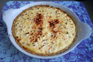 white casserole dish with quiche sprinkled with paprika