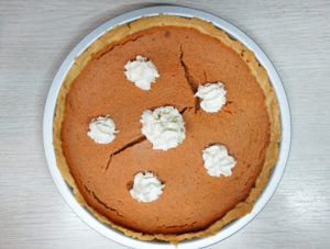 Homemade pumpkin pie with puffs of whipped cream
