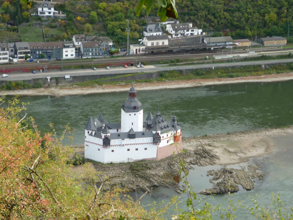 Kaub castle is red and white plaster with gray turrets. It stands on an island in the middle of the Rhine River