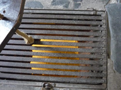 metal grill with rope passing through it to dungeon below