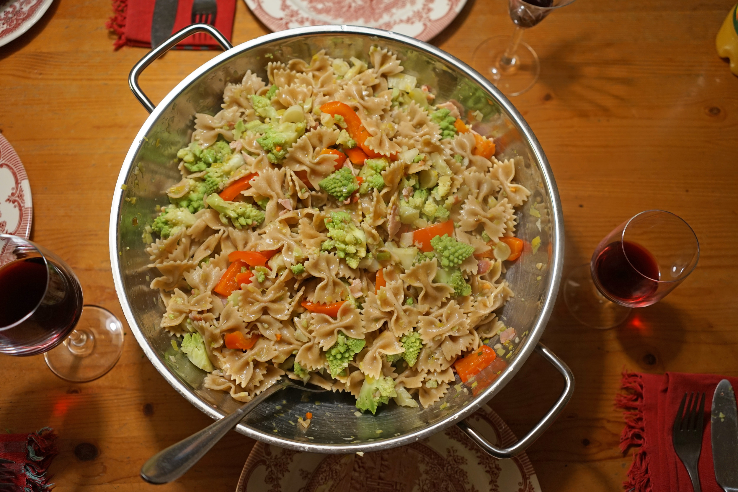 metal wok on table with butterfly pasta, red peppers, romanesco cauliflower that looks like tiny green Christmas trees