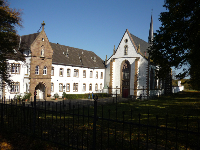 Abbey and church buildings painted white with red trim against a blue sky