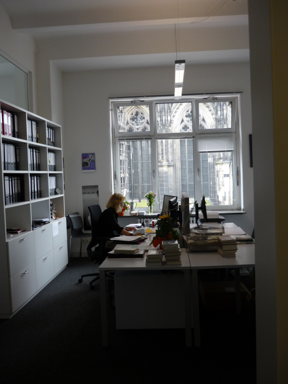 office with Cologne Cathedral visible through the window.