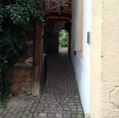 narrow alley leads to arched doorway in stone wall